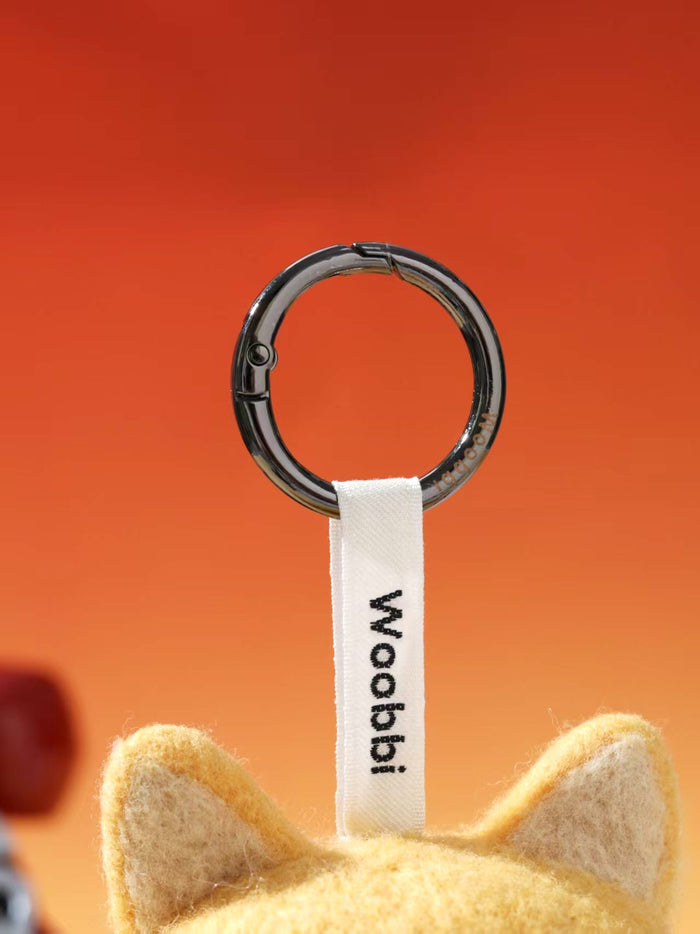 Close-up of durable black metal keychain ring and white woven Woobbi brand tag attached to a wool bag charm.
