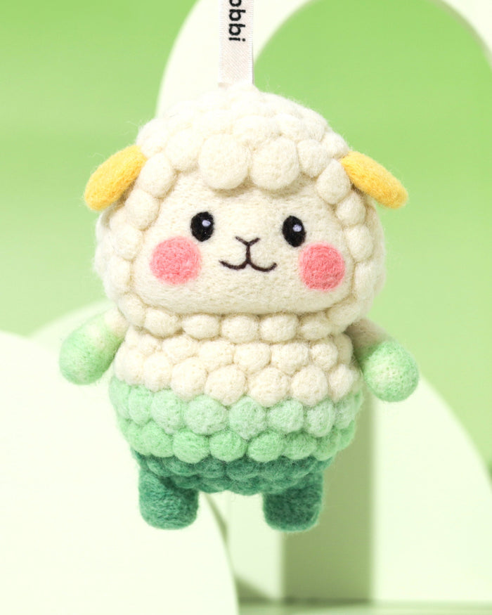 Macro detail of needle-felted sheep face showing the unique bubbly wool texture, rosy pink cheeks, and hand-stitched smile.