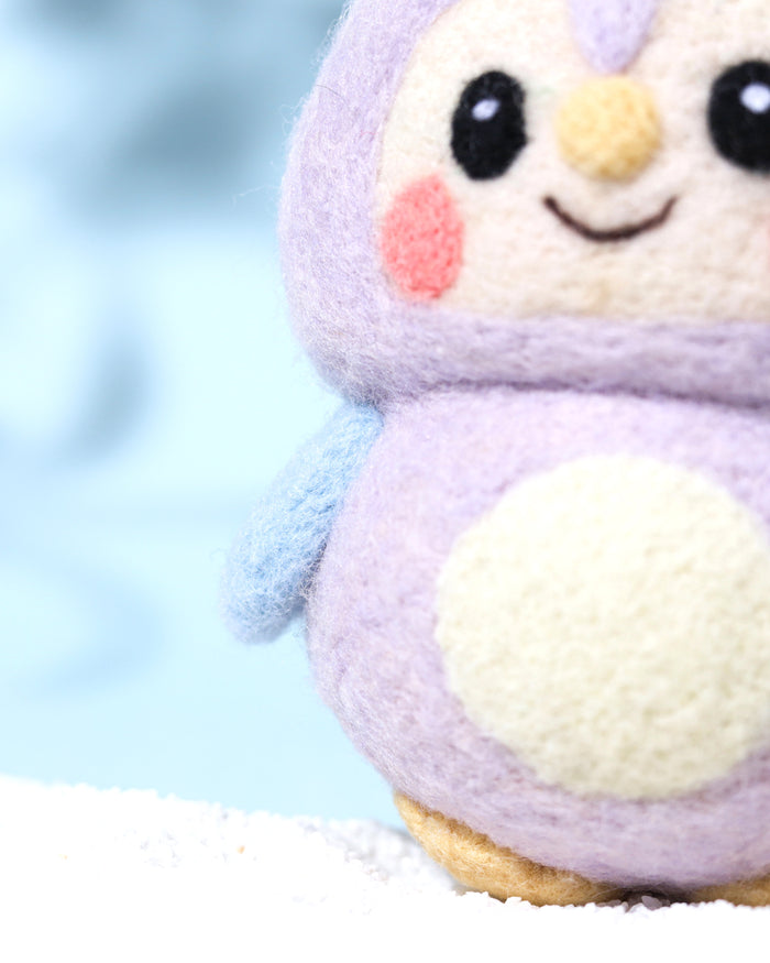 Close-up detail of purple needle-felted owl charm showing the fuzzy natural wool texture, pink blushed cheeks, and heart-shaped face design.